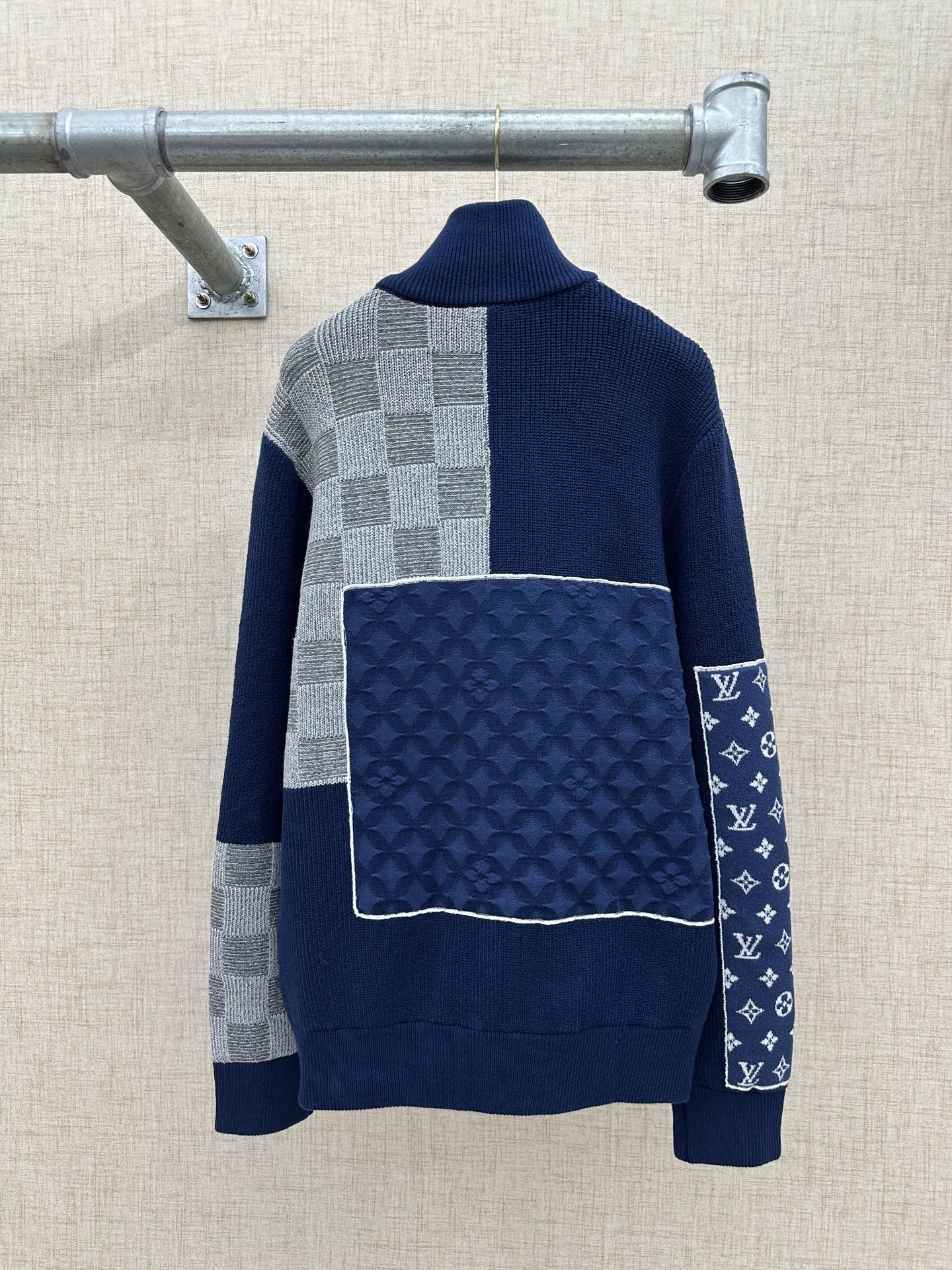 Navy knit sweater jacket with ribbed collar, checkered panels, and large square back patch