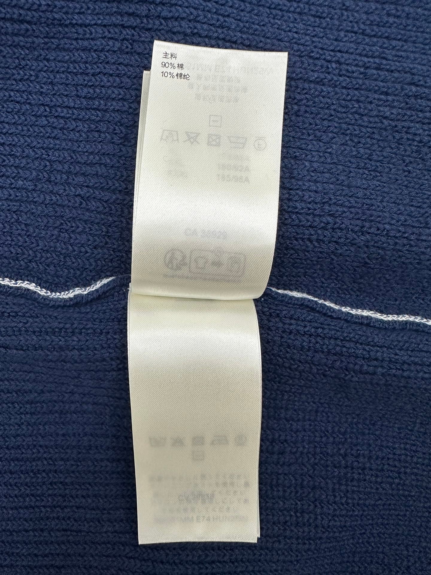 Dark blue knit garment with care and fabric information label on inside