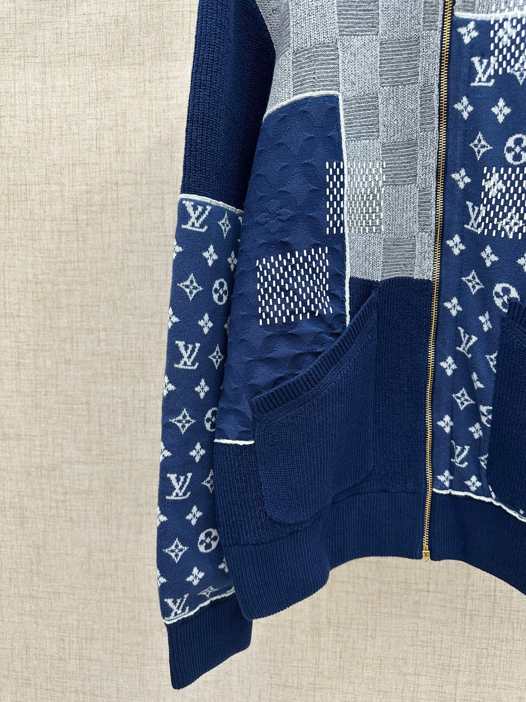 Front view of navy knit jacket with dotted and monogram-style logo patch and zip closure