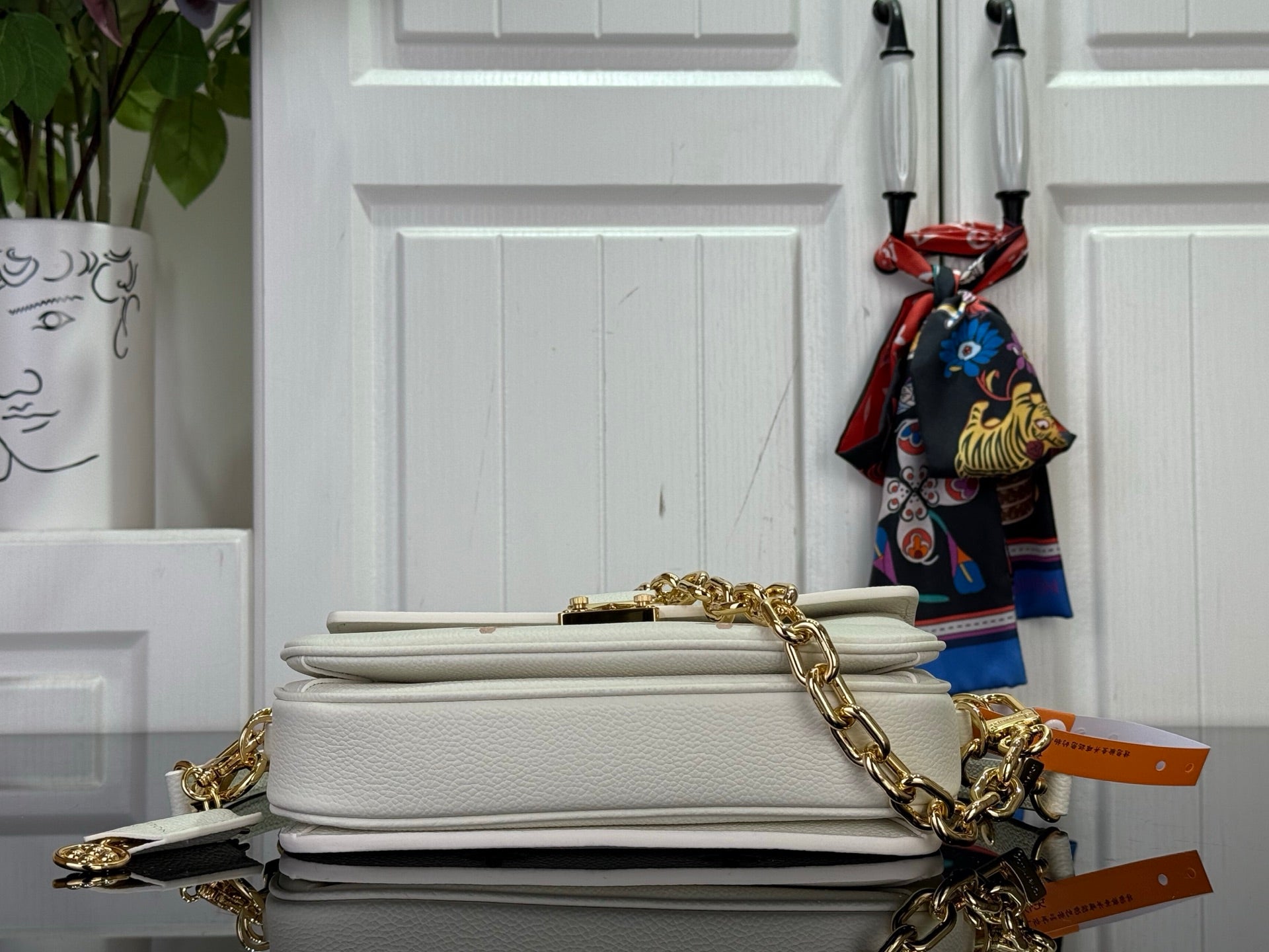 Louis Vuitton crossbody bag with gold chain strap, stacked top view with closure