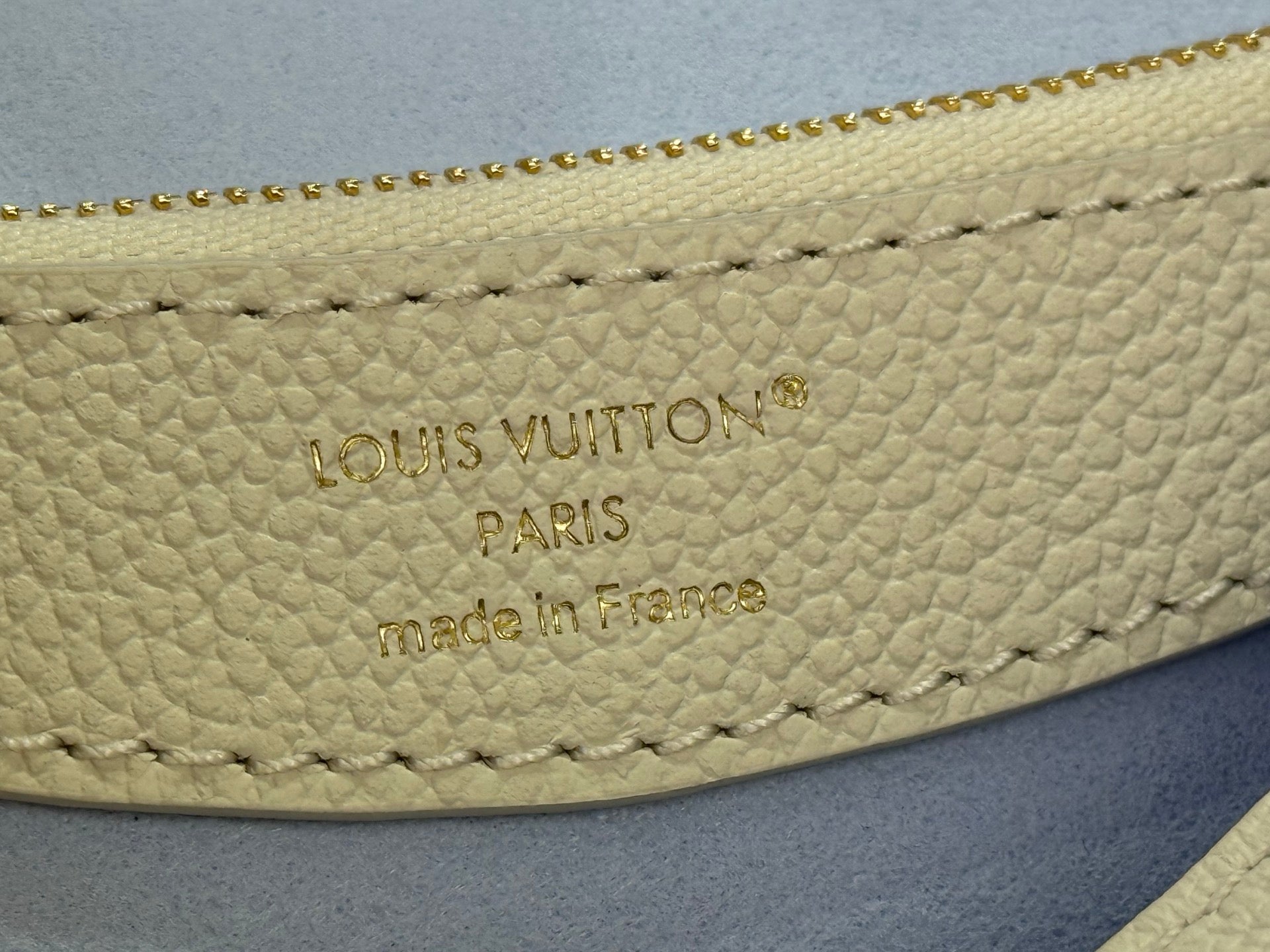 Louis Vuitton Paris embossed on white leather bag, stitched seam