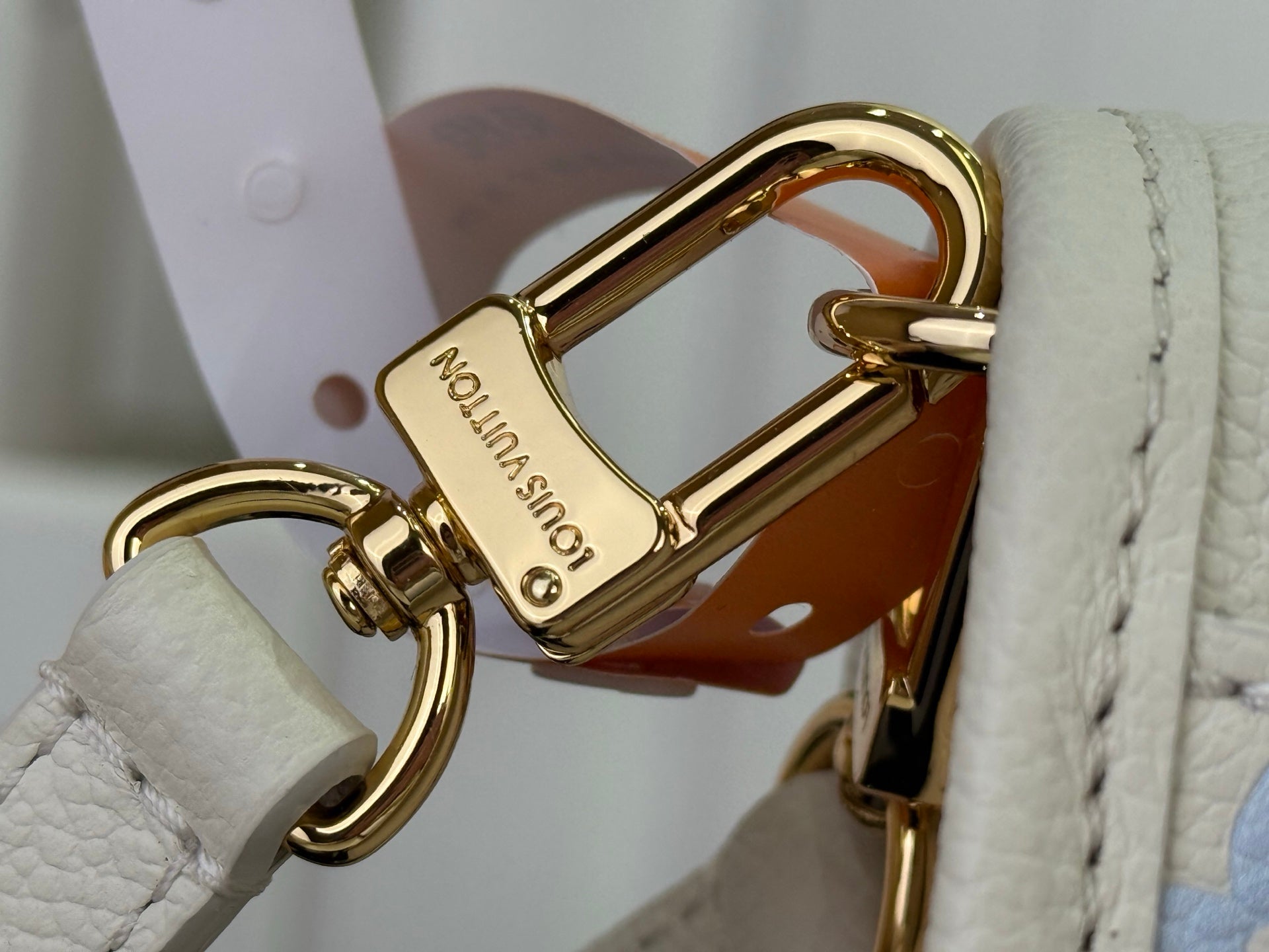 Louis Vuitton gold swivel clasp hardware on white crossbody bag