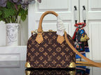 Monogram handbag with tan top handles, gold corner studs, and crossbody strap attached