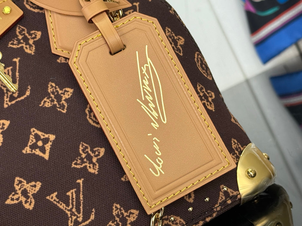 Tan leather luggage tag with gold script, stitched border on brown monogram canvas