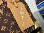 Tan leather luggage tag with gold script, stitched border on brown monogram canvas