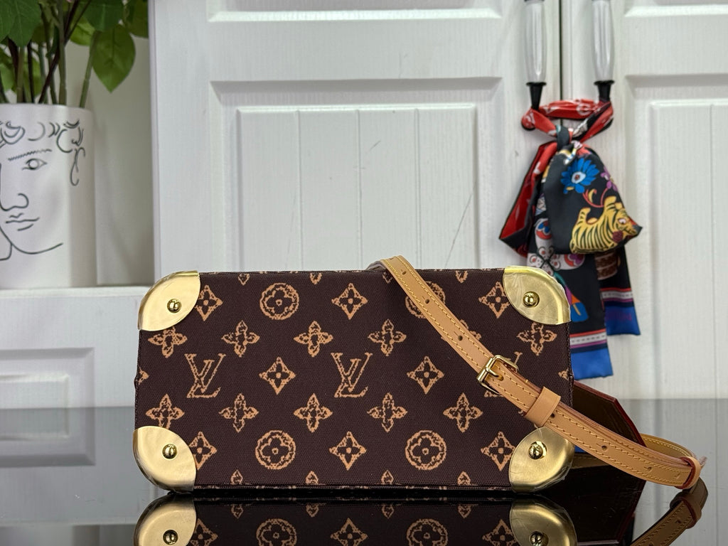 Monogram tote with tan crossbody strap and gold corner feet, front angled view