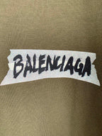 Balenciaga logo print on olive T-shirt chest area, white backing with black text