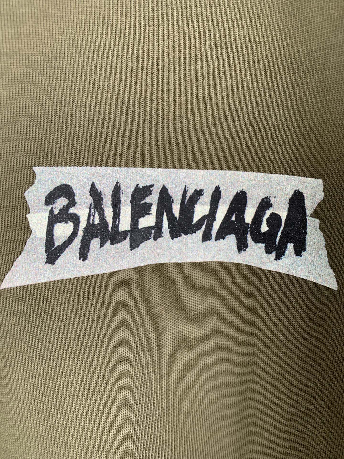 Balenciaga logo print on olive T-shirt chest area, white backing with black text
