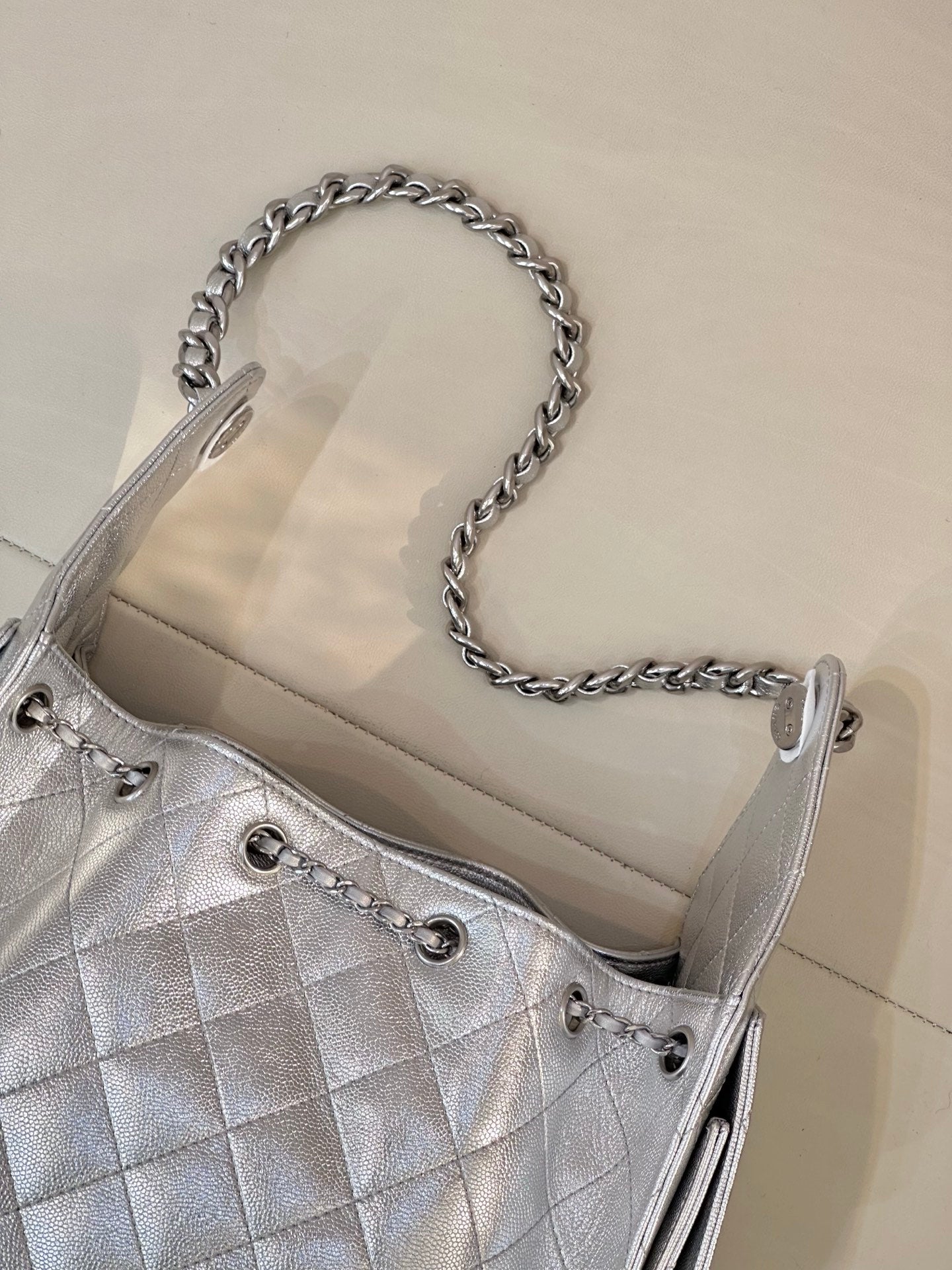 Chanel quilted chain-strap shoulder bag in silver tone, close-up of chain handles and eyelets