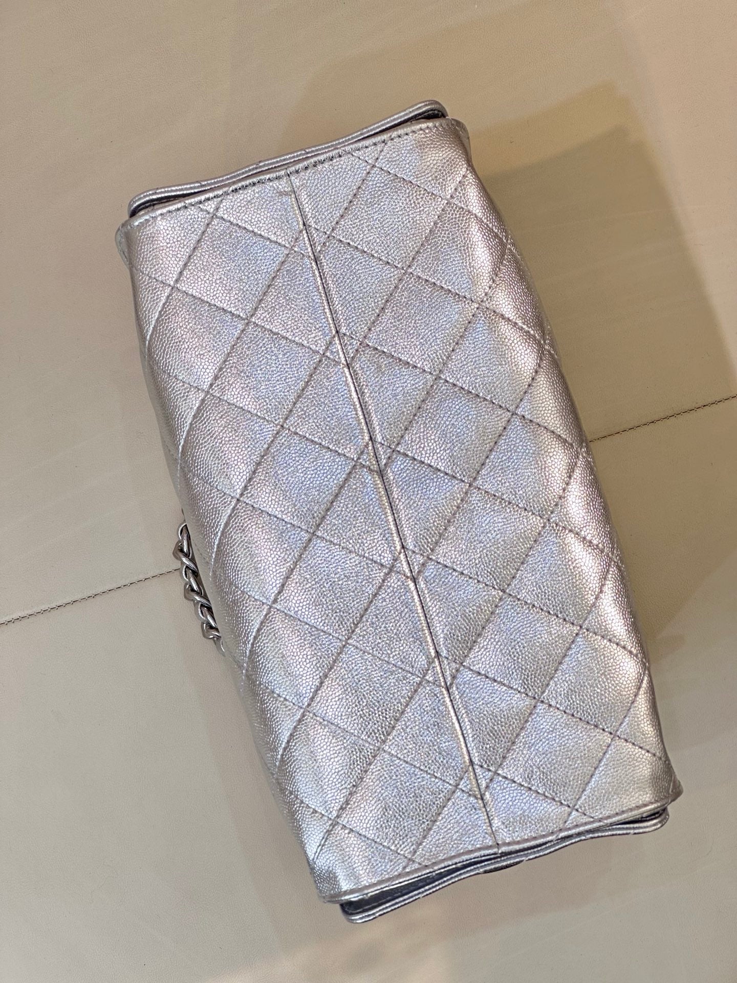 Chanel quilted chain-strap bucket-style bag in silver tone, side profile with tie closure