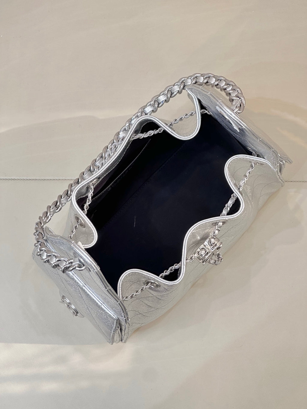 Chanel quilted chain-strap bag in silver tone, open top showing dark interior lining