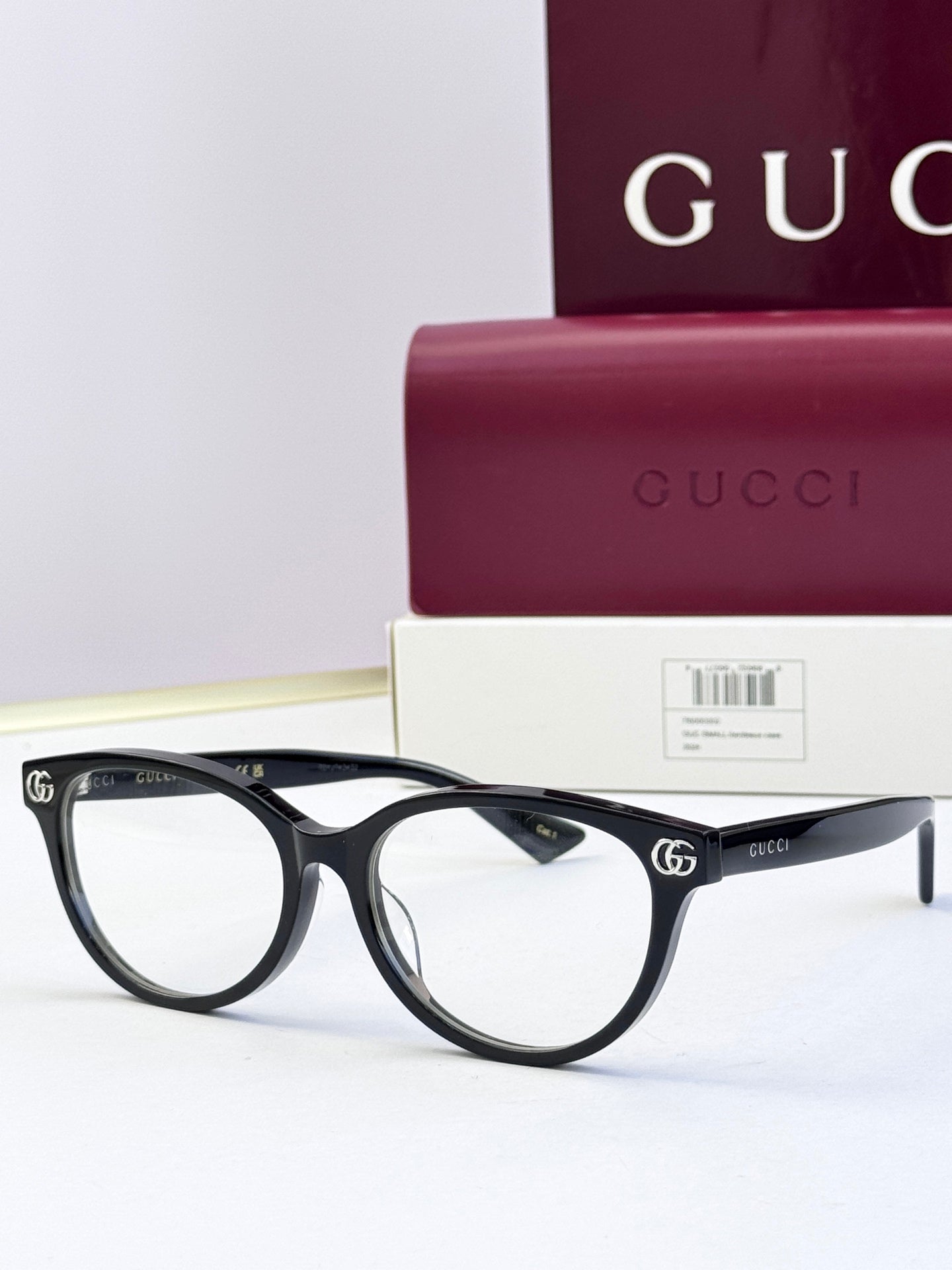 Black eyeglass frames with clear lenses and gold logo detail at temples
