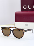 Tortoiseshell eyeglass frames with brown lenses and gold logo detail at temples