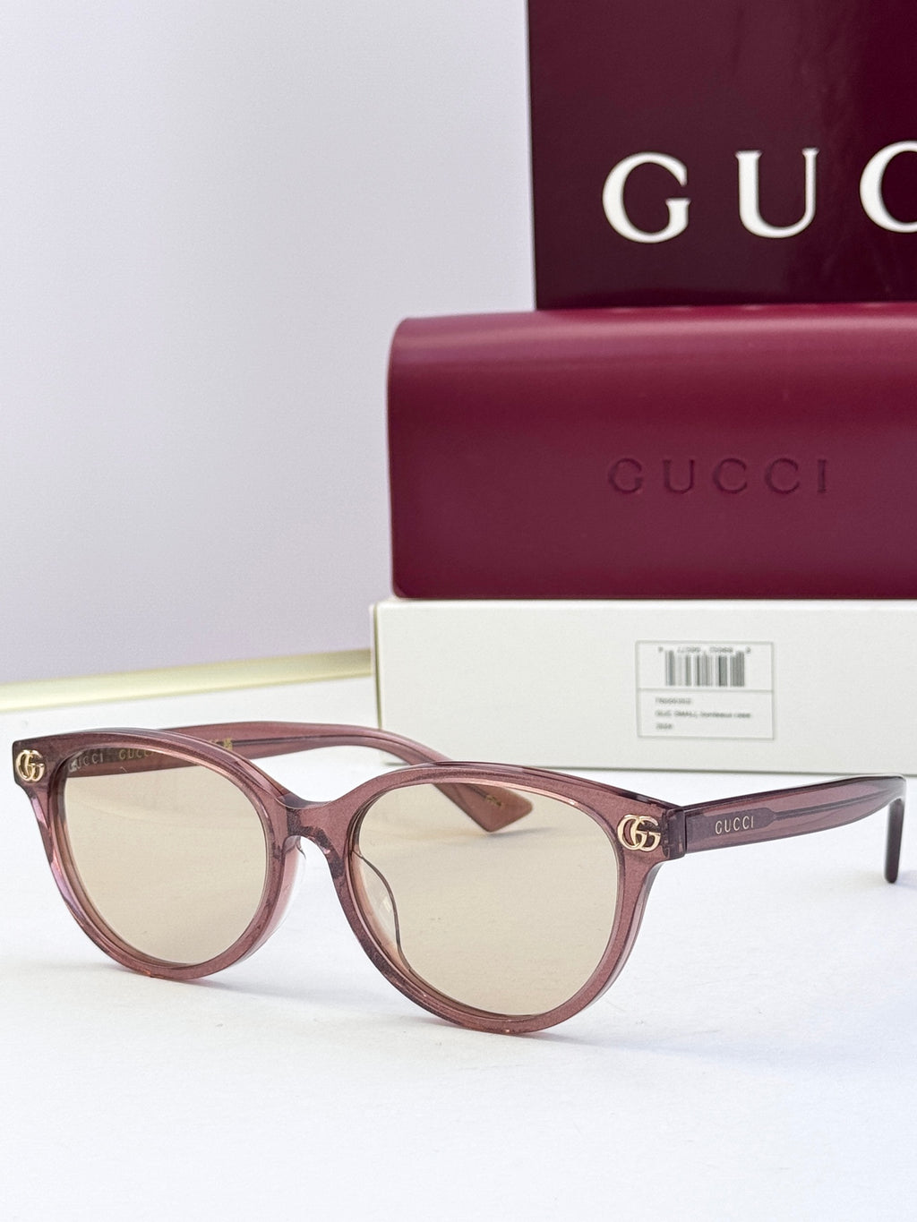 Burgundy eyeglass frames with clear lenses and gold logo detail at temples