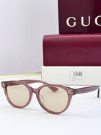Burgundy eyeglass frames with clear lenses and gold logo detail at temples