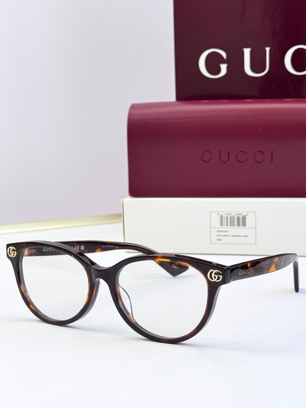 Tortoiseshell eyeglass frames with clear lenses and gold logo detail at temples