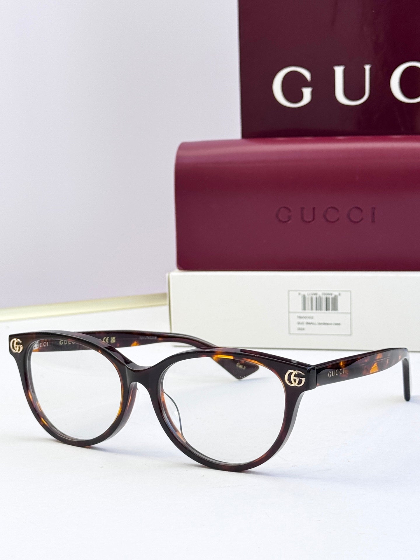 Tortoiseshell eyeglass frames with clear lenses and gold logo detail at temples