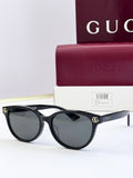 Black eyeglass frames with dark lenses and gold logo detail at temples