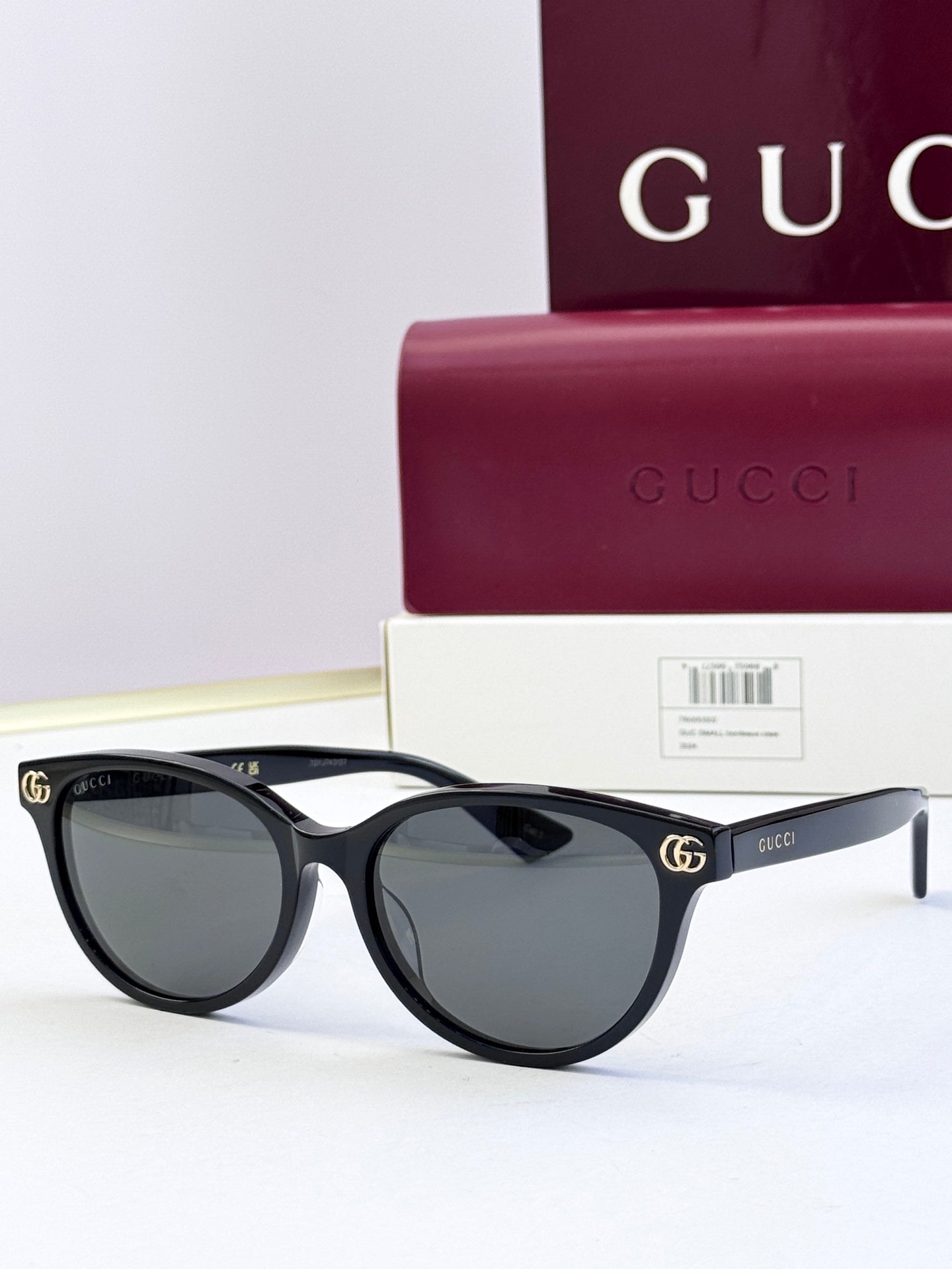 Black eyeglass frames with dark lenses and gold logo detail at temples