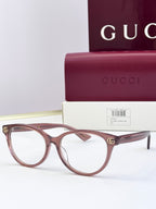 Burgundy eyeglass frames with clear lenses and gold logo detail at temples