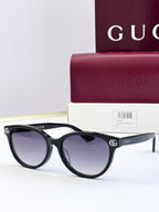 Black eyeglass frames with tinted lenses and gold logo detail at temples