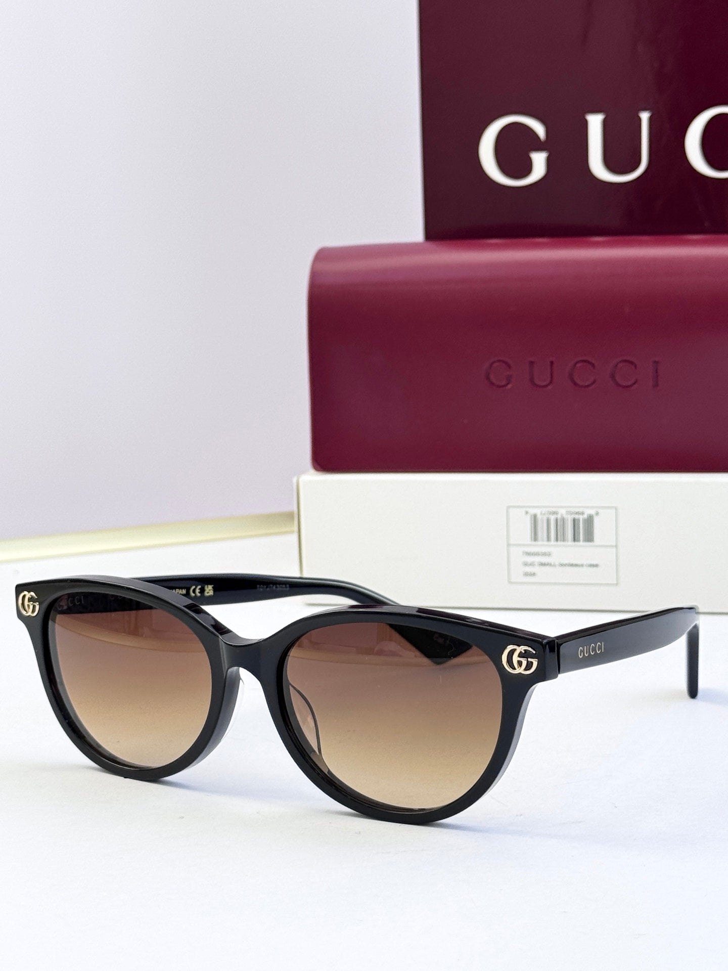 Black eyeglass frames with warm brown lenses and gold logo detail at temples