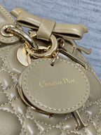 Dior quilted mini handbag detail with gold hardware and round engraved charm tag