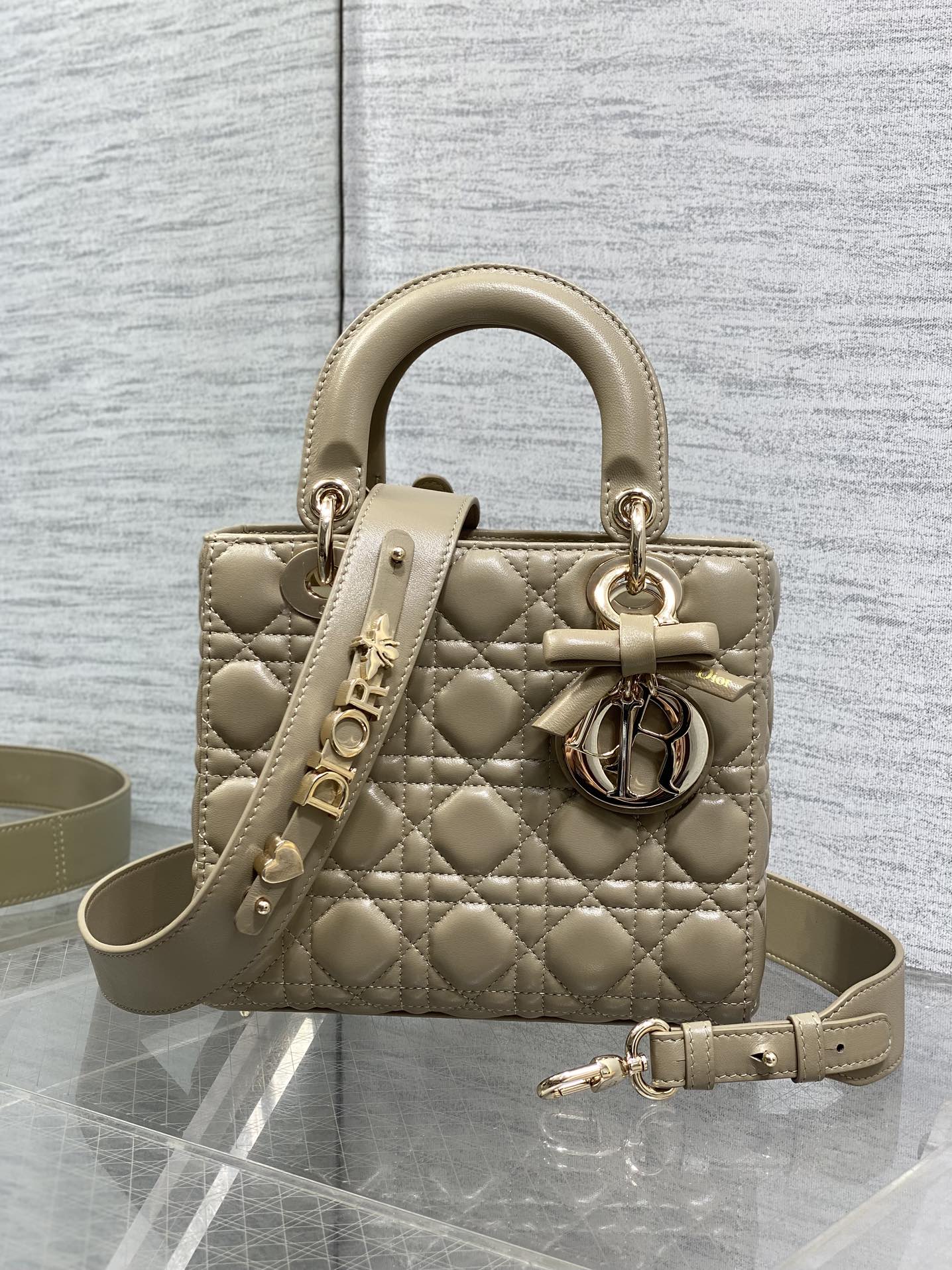 Dior quilted mini handbag in beige with top handle, bow charm, and shoulder strap