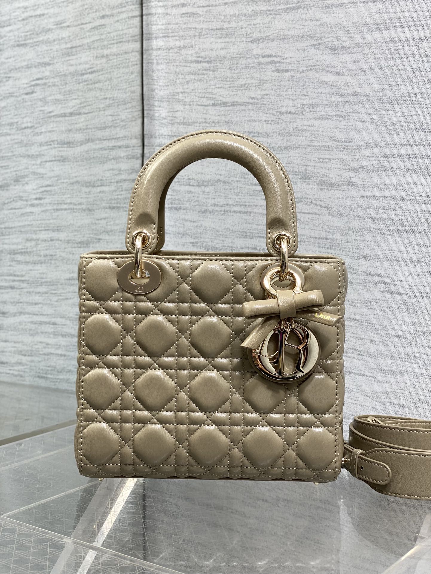 Dior quilted mini handbag in beige with bow charm, gold hardware, and shoulder strap