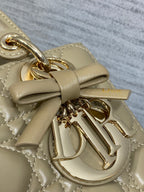 Dior quilted handbag close-up with bow detail and gold-tone dangling key charm