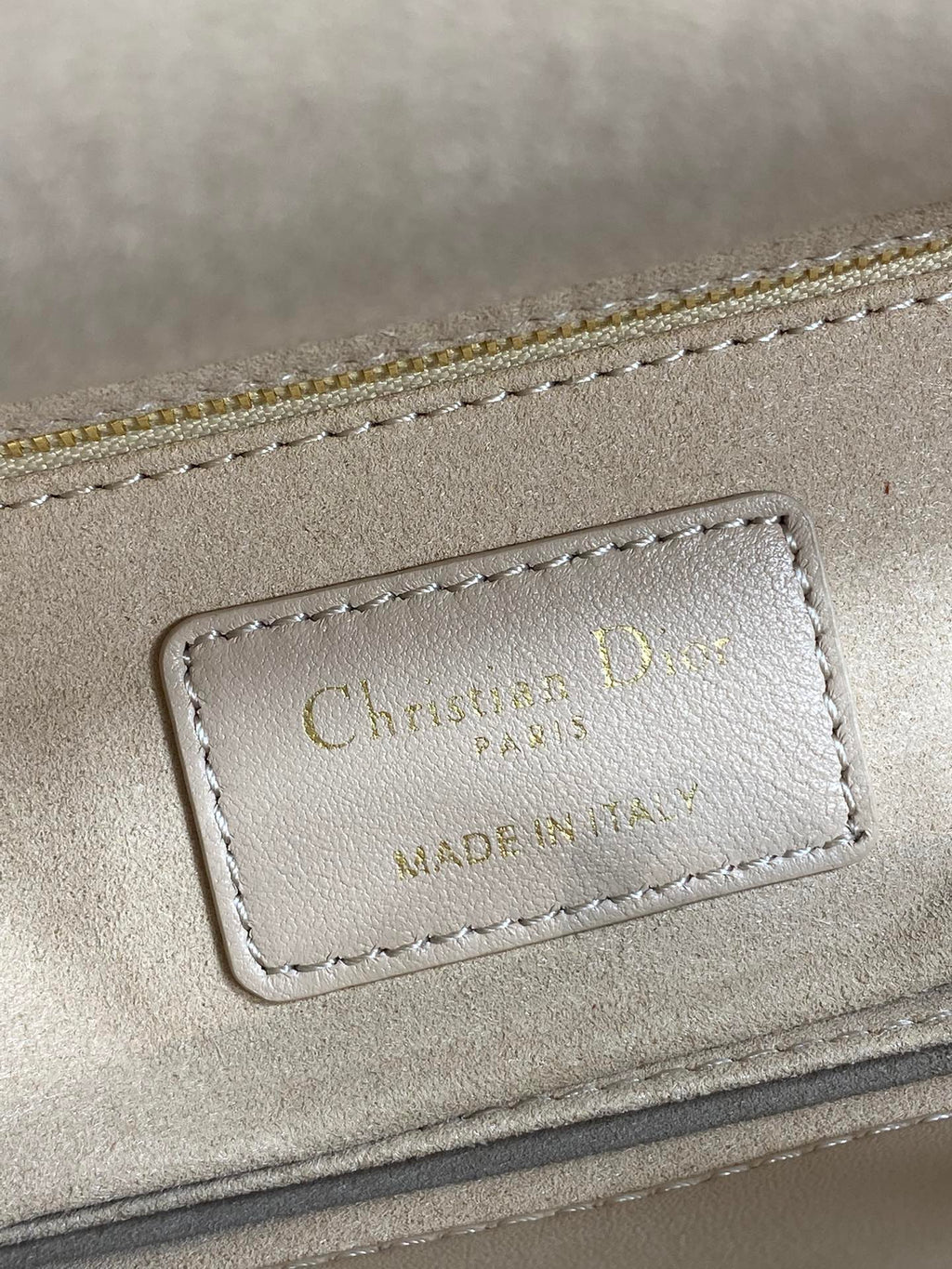 Dior embossed label on beige quilted handbag with stitching and gold-tone trim