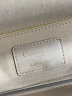 Dior embossed label on beige quilted handbag with stitching and gold-tone trim