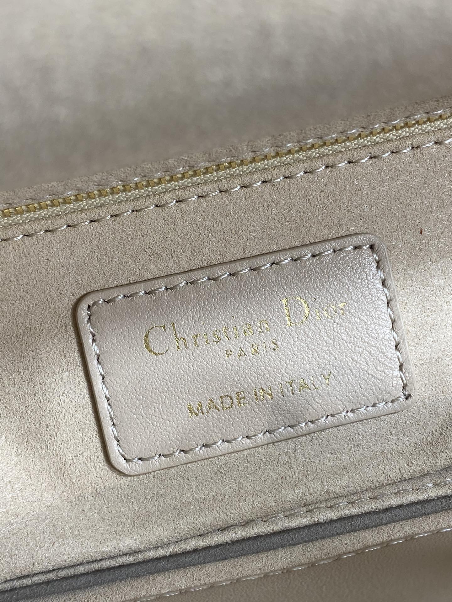 Dior embossed label on beige quilted handbag with stitching and gold-tone trim