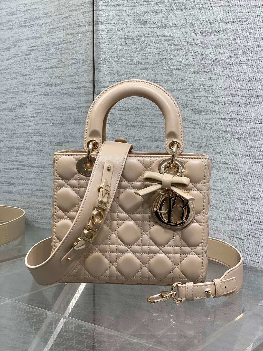 Dior quilted beige mini handbag with top handles, bow charm, and gold-tone hardware