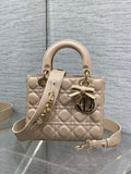 Dior quilted beige mini handbag with top handles, bow charm, and gold-tone hardware