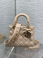 Dior quilted beige mini handbag with top handles, bow charm, and gold-tone hardware