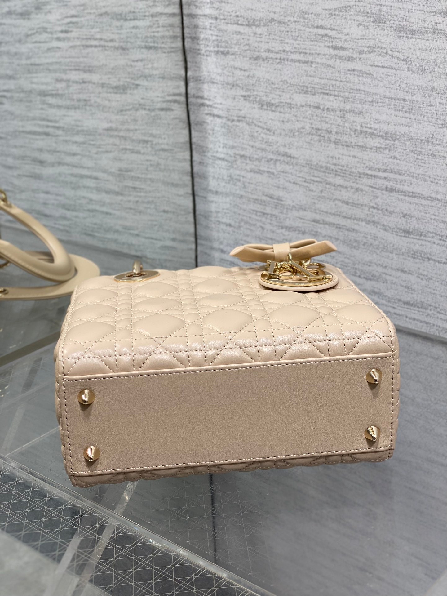 Dior quilted beige mini handbag with side strap, gold studs, and short top handle