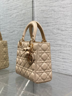 Dior quilted beige handbag from side view with bow charm and gold-tone hardware