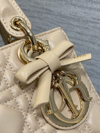 Dior charm clasp detail on quilted beige mini handbag with gold-tone hardware