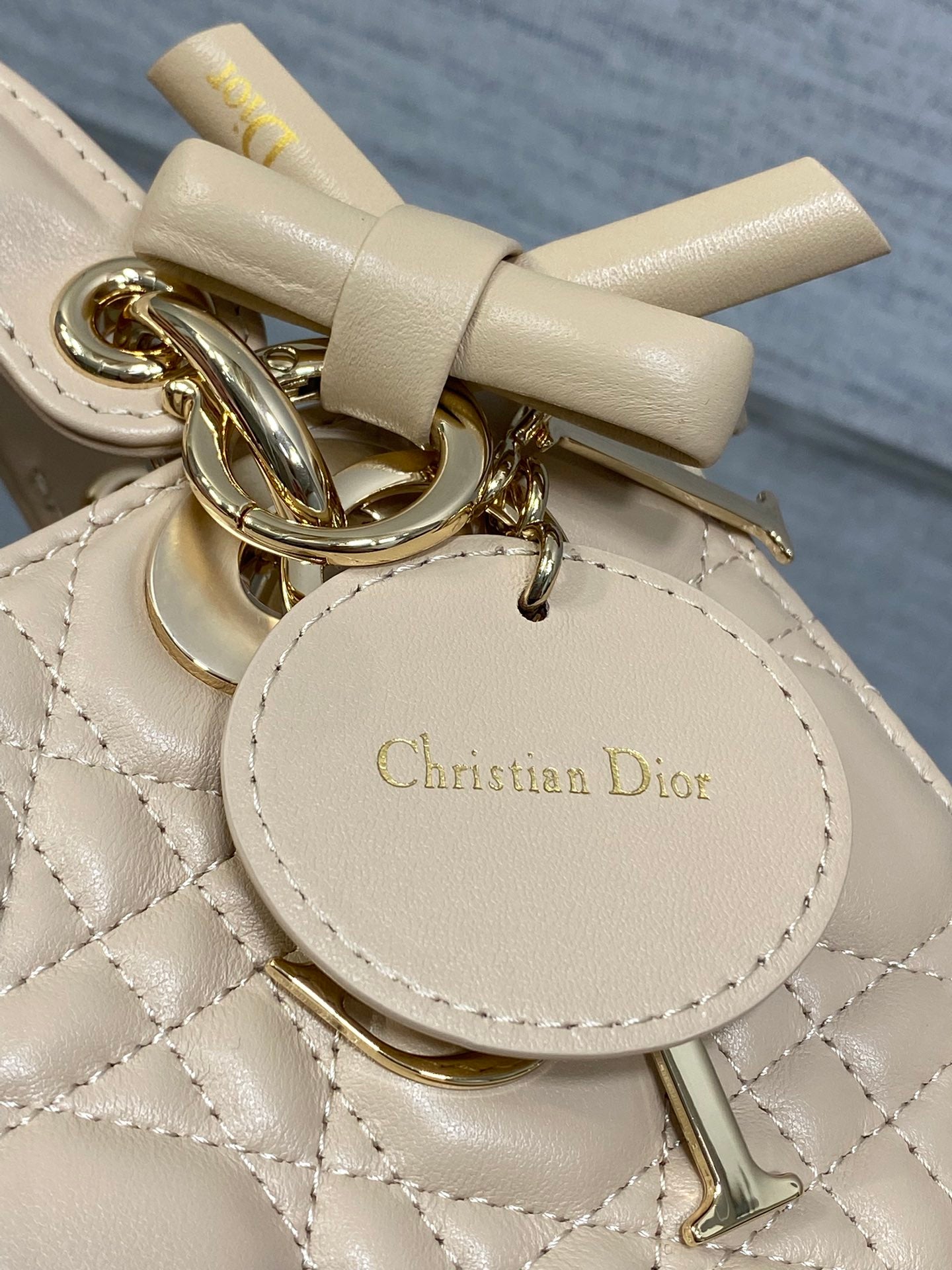 Dior leather tag and gold-tone keyring charm on quilted beige mini handbag