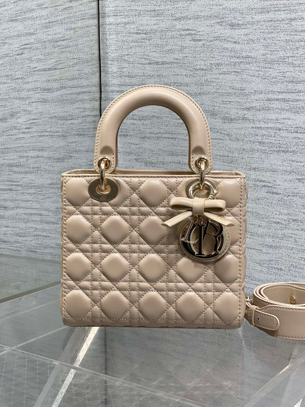 Dior quilted beige handbag with short top handles, bow detail, and crossbody strap
