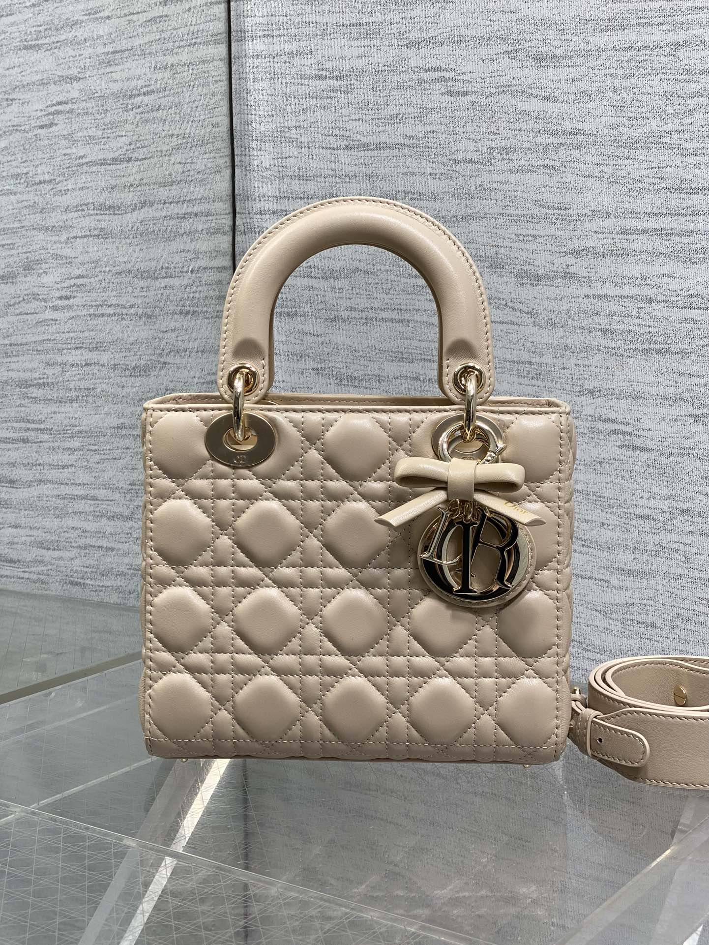 Dior quilted beige handbag with short top handles, bow detail, and crossbody strap