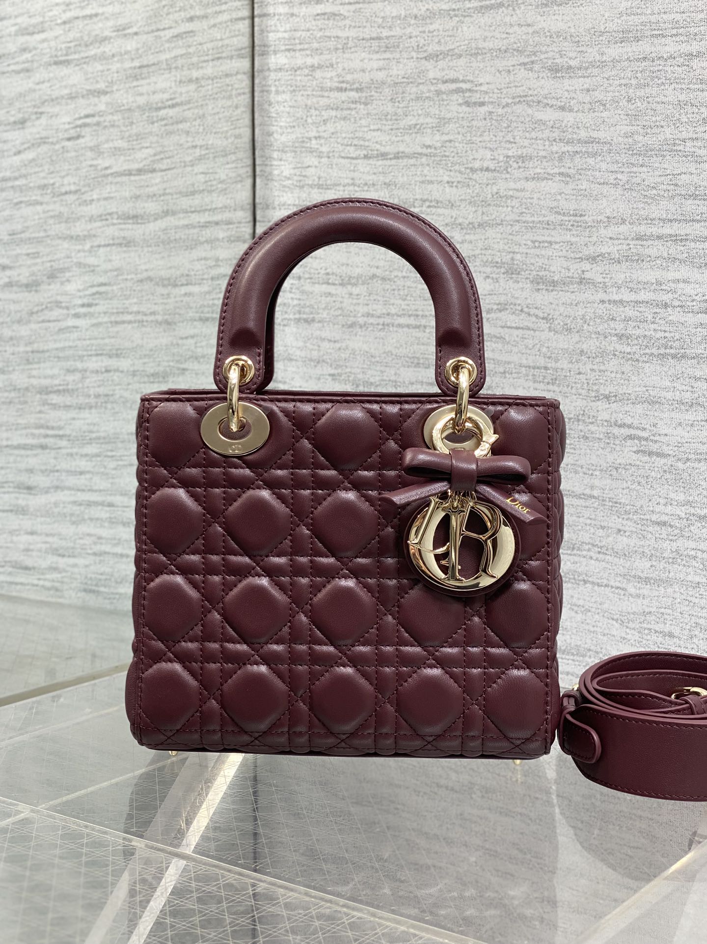 Burgundy quilted mini handbag with top handles, gold rings, and shoulder strap
