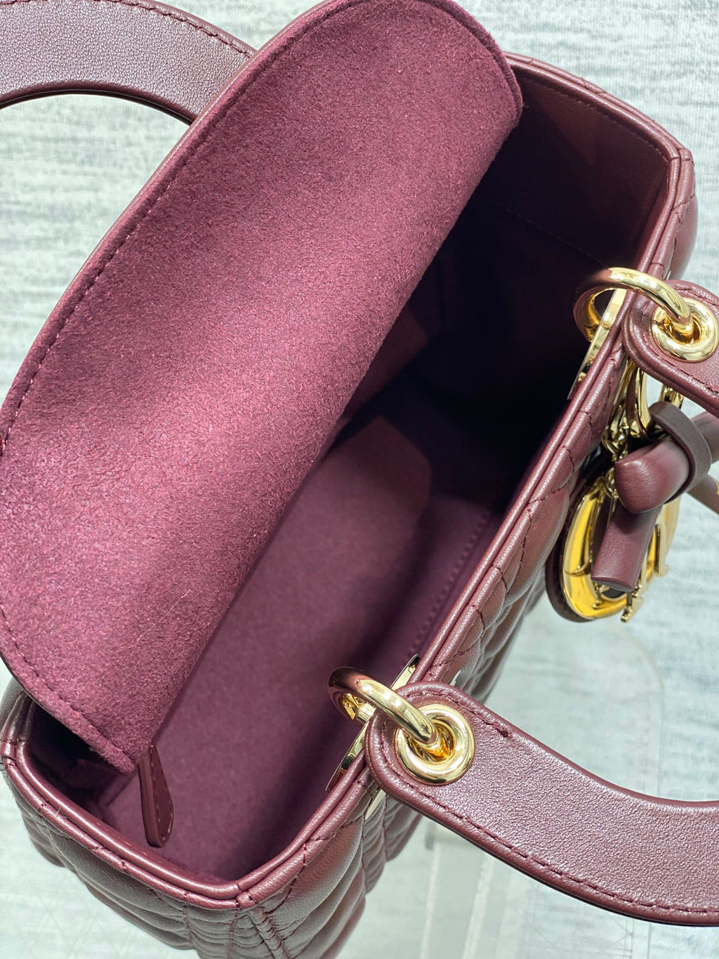 Burgundy mini bag opening showing fabric lining and gold clasp hardware