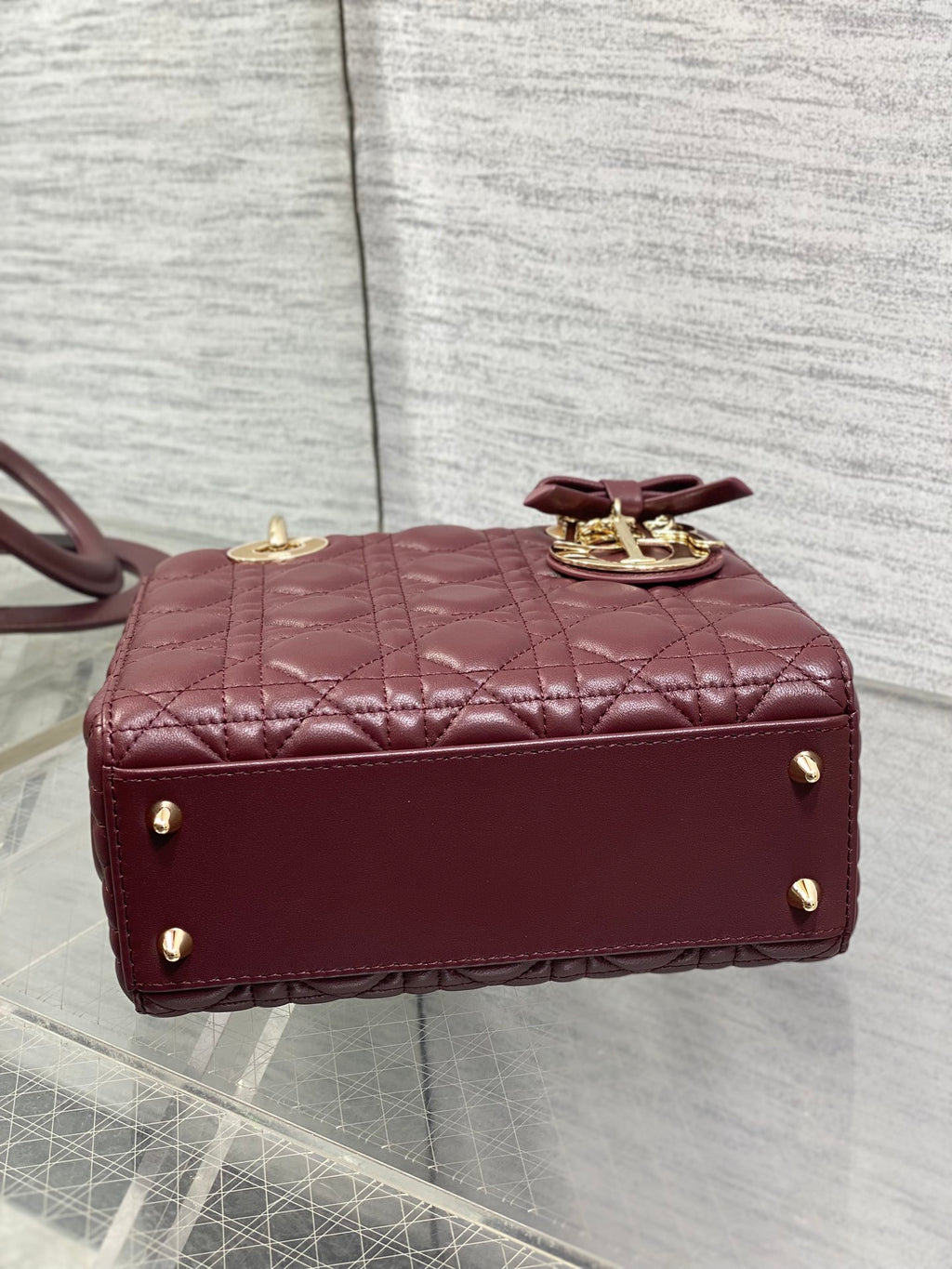 Burgundy quilted mini handbag back view with gold studs and short top handle