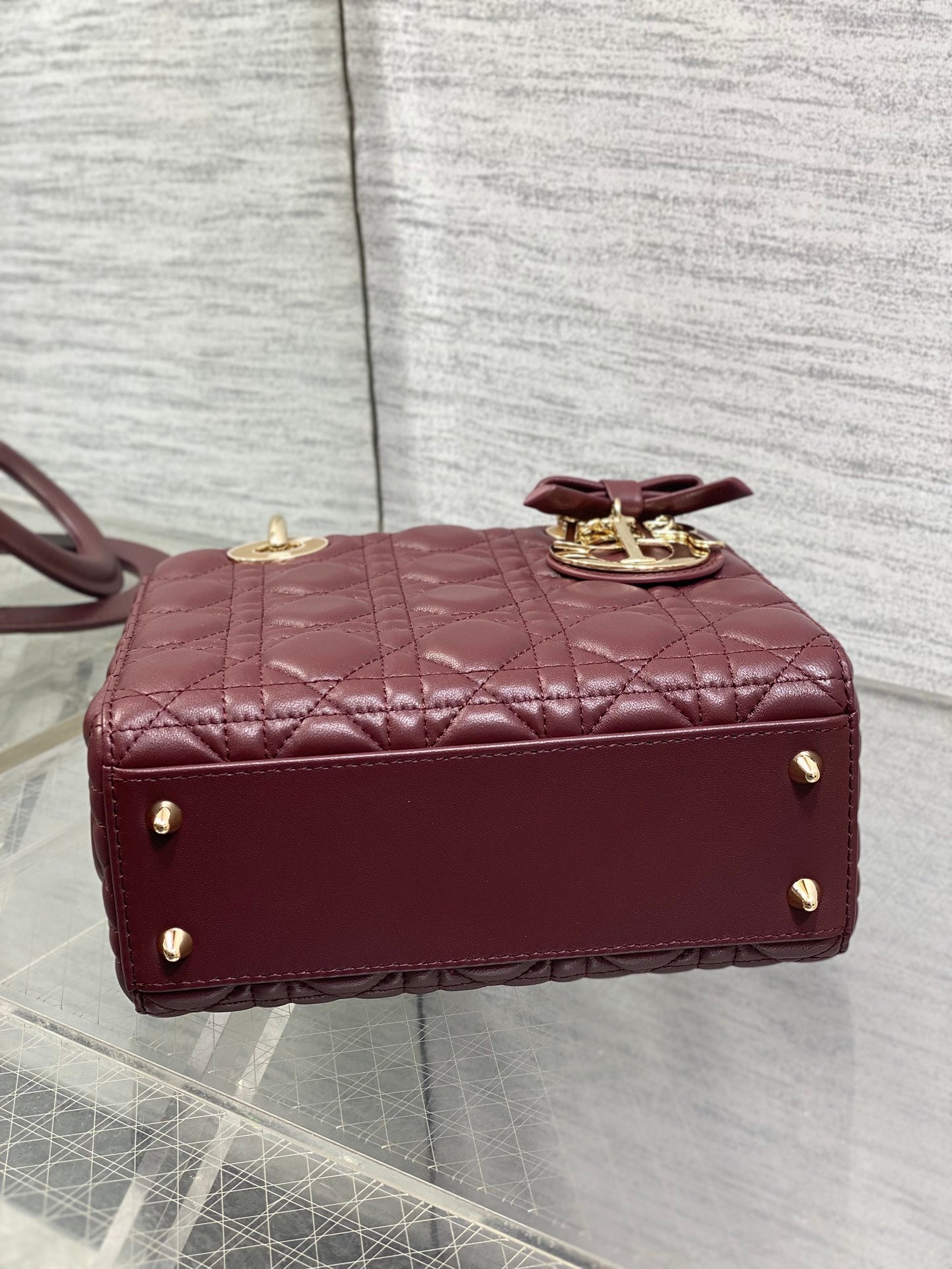 Burgundy quilted mini handbag back view with gold studs and short top handle