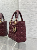Burgundy quilted mini tote with top handles and gold-tone charm on the strap