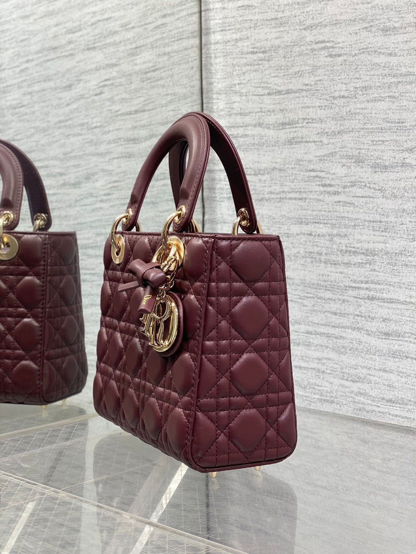 Burgundy quilted mini tote with top handles and gold-tone charm on the strap