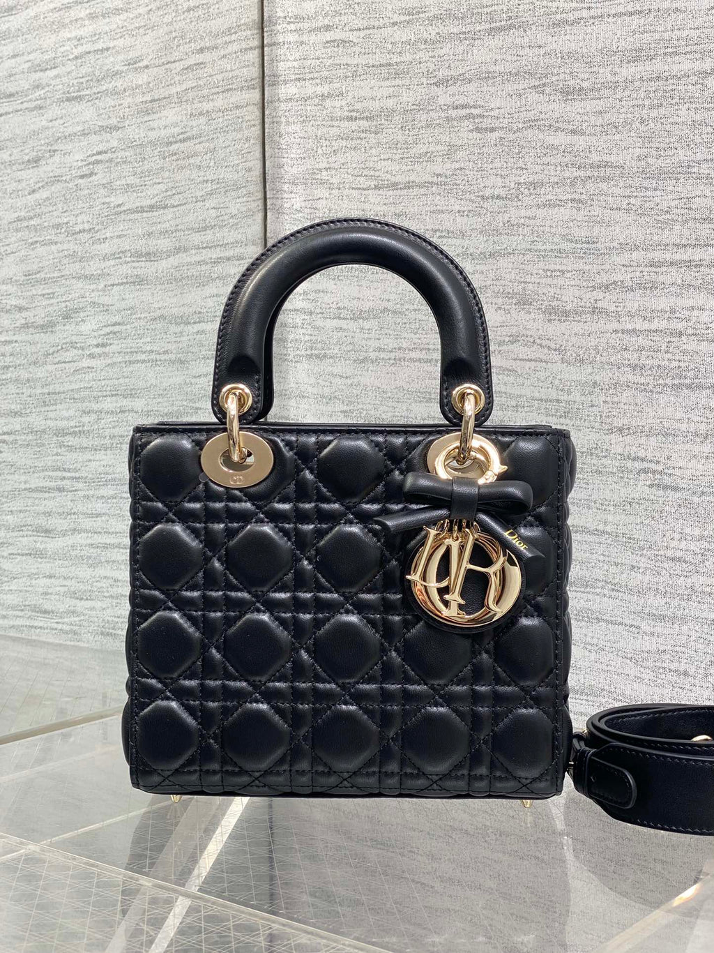 Black quilted mini handbag with structured top handle and gold-tone logo charm