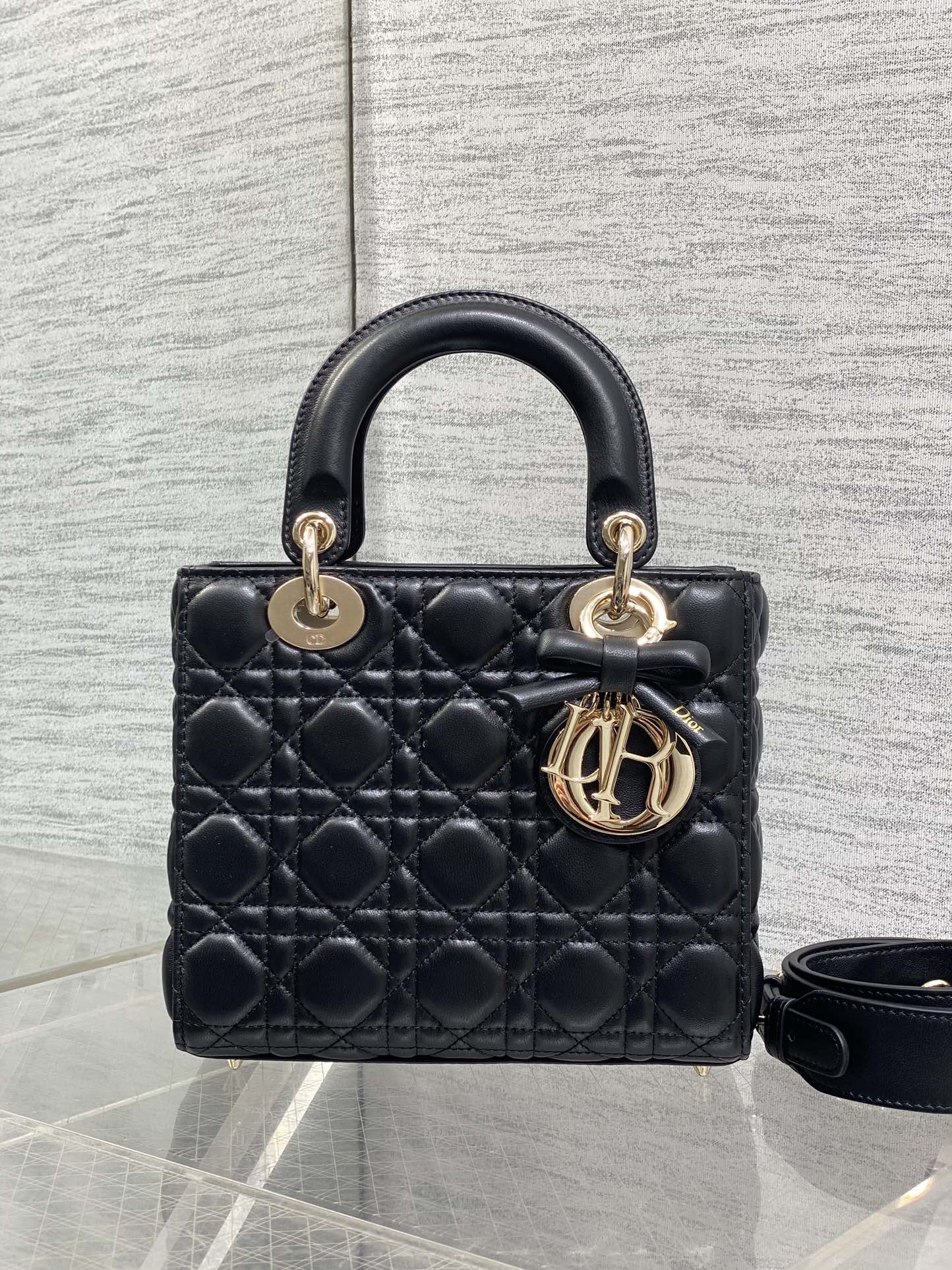 Black quilted mini handbag with structured top handle and gold-tone logo charm